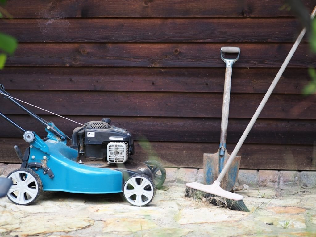 green-and-black-push-lawn-mower-beside-brown-wooden-wall-hvedb6rvt4q
